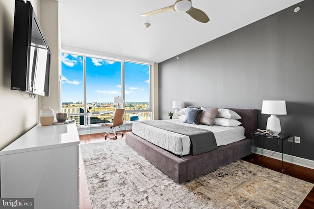 bedroom with a wall of windows, wood finished floors, baseboards, and ceiling fan