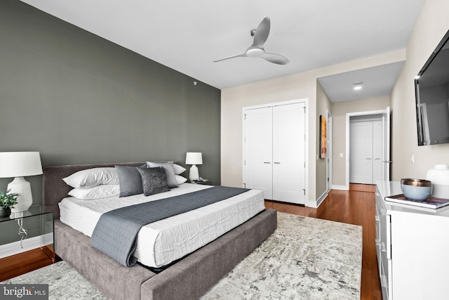 bedroom featuring dark wood-style floors, ceiling fan, baseboards, and a closet