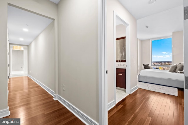 hallway with a sink, baseboards, and wood-type flooring