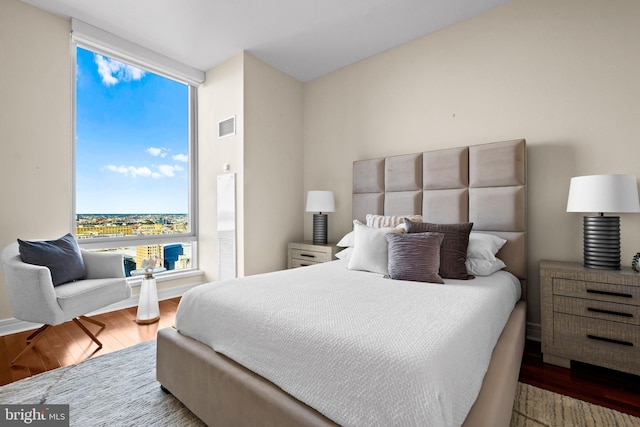 bedroom featuring visible vents, floor to ceiling windows, and wood finished floors