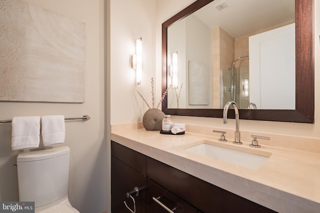 bathroom with vanity, toilet, a shower, and visible vents