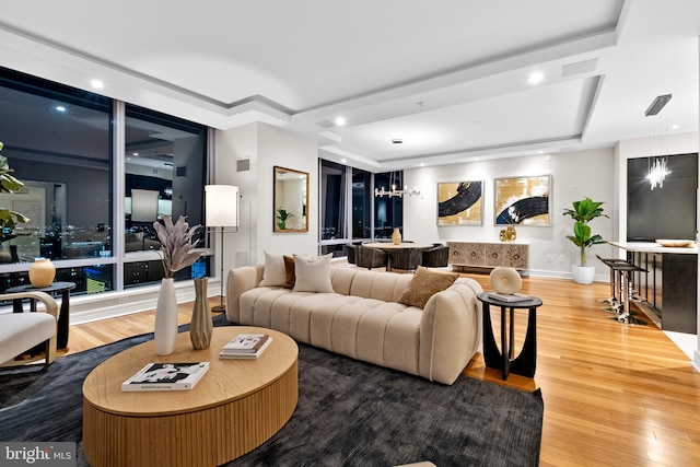 living room with a tray ceiling, visible vents, and wood finished floors