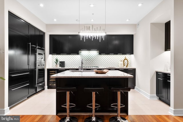 kitchen featuring light stone counters, dark cabinets, appliances with stainless steel finishes, and a sink