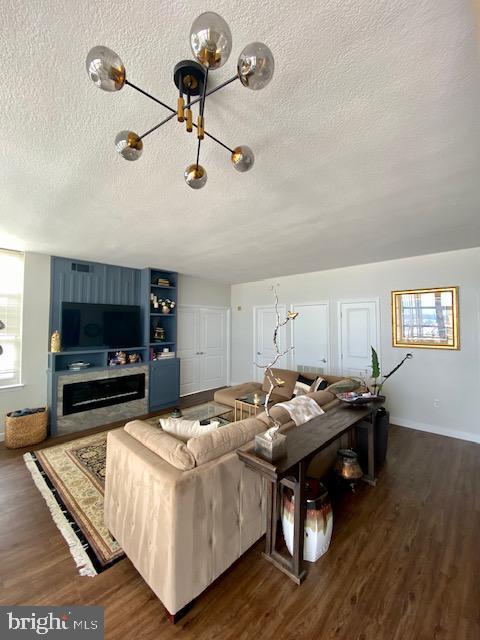 living room with dark wood-style floors, a fireplace, a textured ceiling, and baseboards