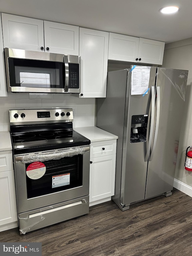 kitchen with light countertops, white cabinets, dark wood-style floors, and stainless steel appliances