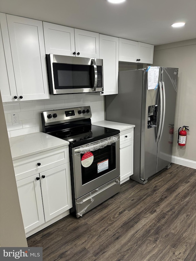 kitchen featuring dark wood-style floors, backsplash, appliances with stainless steel finishes, and white cabinetry