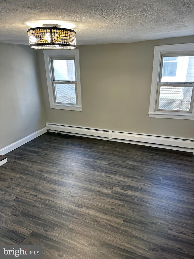 unfurnished room featuring dark wood-style floors, baseboard heating, and a textured ceiling