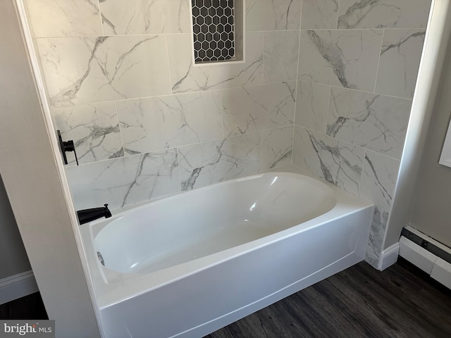 full bathroom with a baseboard heating unit, a bathing tub, and wood finished floors