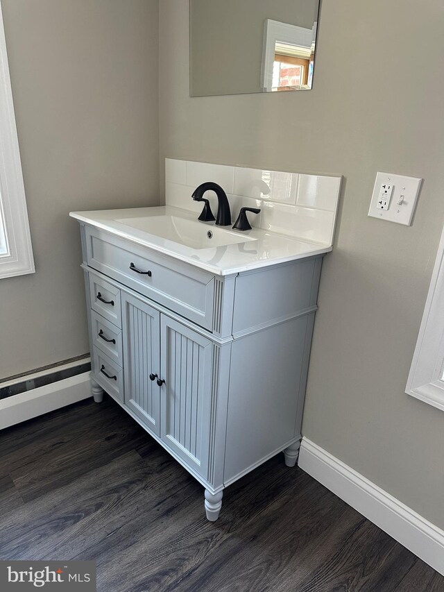 bathroom featuring vanity, decorative backsplash, wood finished floors, and baseboards