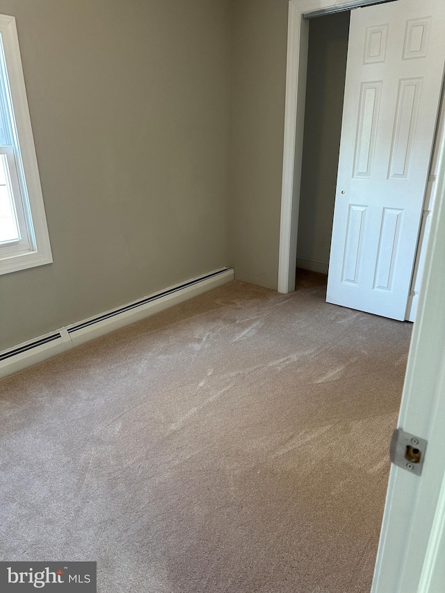 unfurnished bedroom with a baseboard radiator and carpet flooring