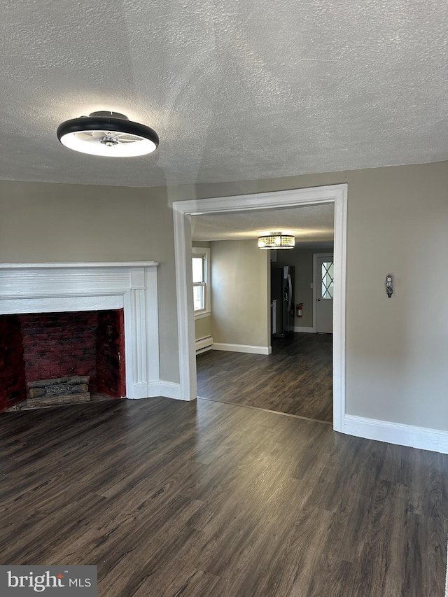 unfurnished living room with a baseboard heating unit, baseboards, dark wood-style floors, and a fireplace