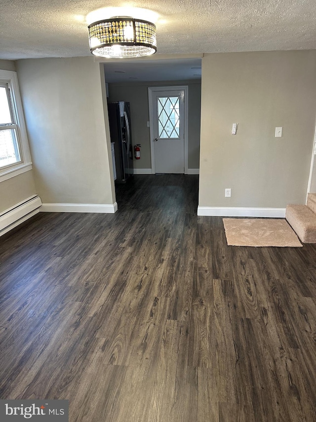 unfurnished dining area featuring baseboards, a textured ceiling, and dark wood-style floors