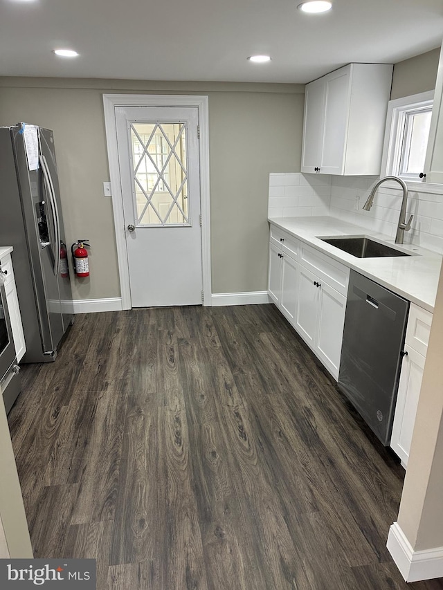 kitchen featuring a sink, tasteful backsplash, dark wood-style floors, stainless steel appliances, and light countertops