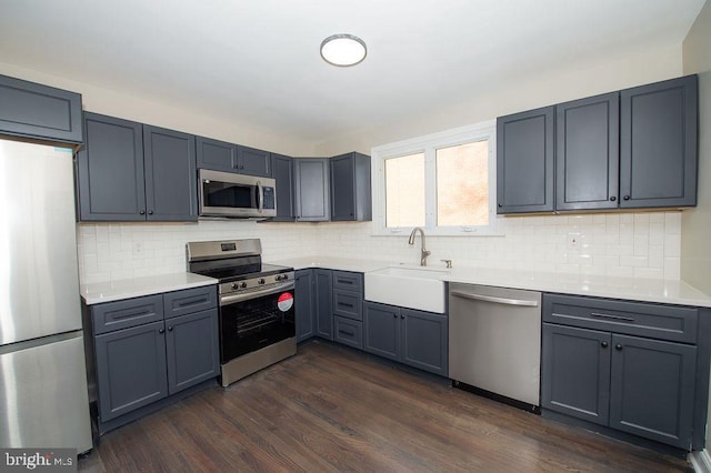 kitchen featuring a sink, appliances with stainless steel finishes, dark wood finished floors, and light countertops