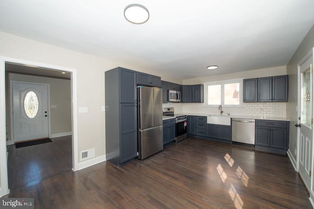 kitchen featuring a sink, light countertops, dark wood-style flooring, and stainless steel appliances