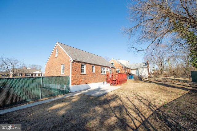 rear view of property featuring a wooden deck, brick siding, a yard, and fence