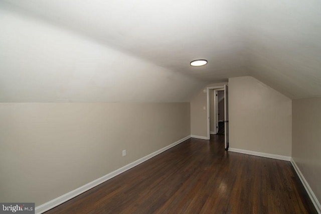 bonus room featuring dark wood-type flooring, baseboards, and lofted ceiling