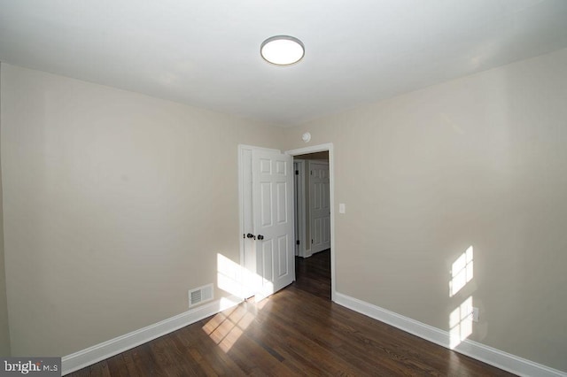 unfurnished room featuring visible vents, baseboards, and dark wood finished floors