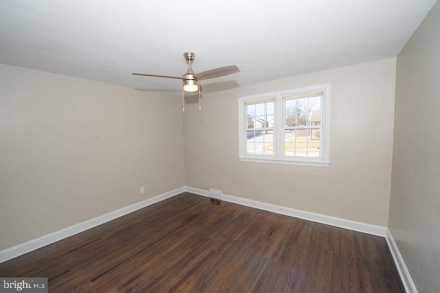 empty room with dark wood-style floors, a ceiling fan, and baseboards