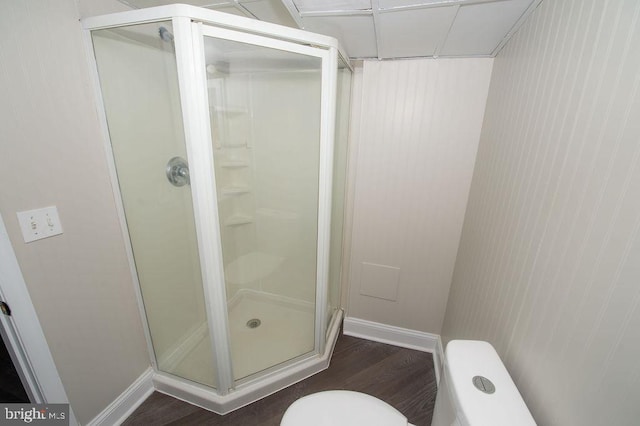 bathroom with a shower stall, toilet, wood finished floors, and baseboards