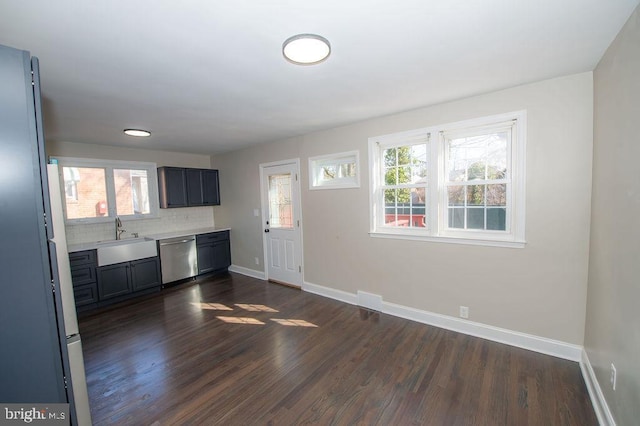 kitchen with dark wood-type flooring, a sink, light countertops, baseboards, and dishwasher