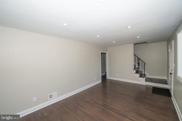 empty room featuring recessed lighting, baseboards, dark wood-style floors, and stairs