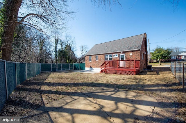 rear view of house with a yard, a fenced backyard, brick siding, and a wooden deck