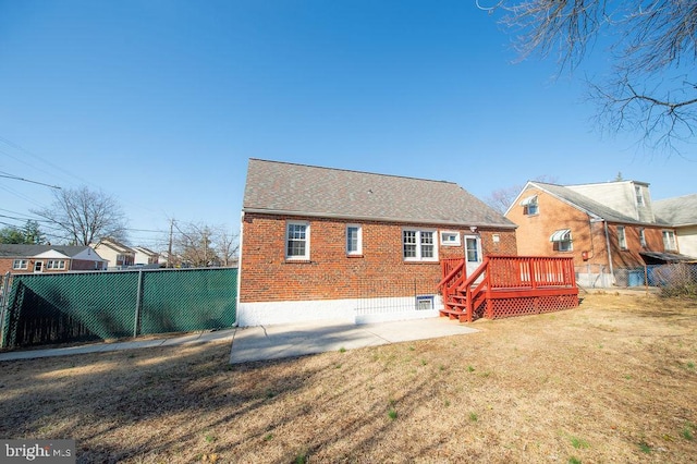 rear view of property featuring a deck, a yard, fence, and brick siding