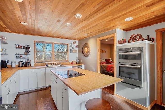 kitchen featuring a sink, wood counters, white cabinetry, double oven, and wood ceiling