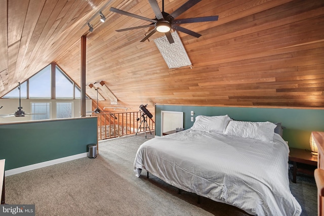 unfurnished bedroom with wooden walls, wooden ceiling, rail lighting, carpet flooring, and vaulted ceiling