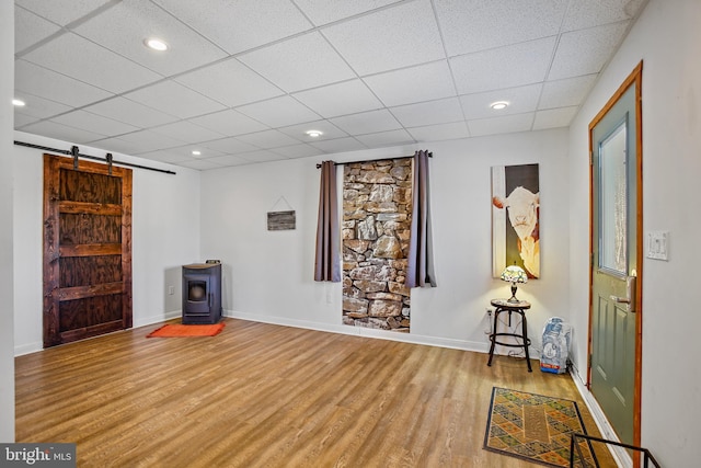 interior space featuring baseboards, a barn door, recessed lighting, wood finished floors, and a paneled ceiling