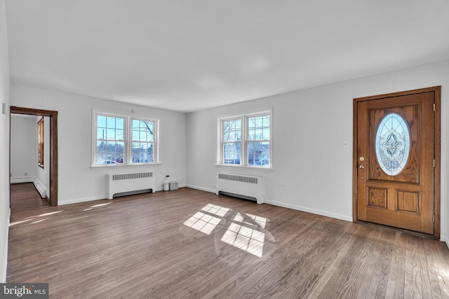 entrance foyer with radiator, wood finished floors, and baseboards