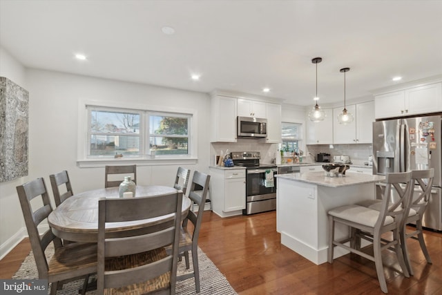 kitchen featuring tasteful backsplash, a healthy amount of sunlight, dark wood-type flooring, appliances with stainless steel finishes, and white cabinets