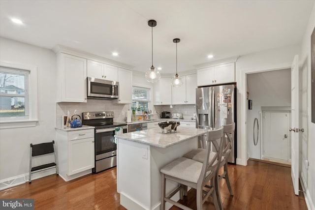 kitchen with backsplash, white cabinetry, stainless steel appliances, and wood finished floors