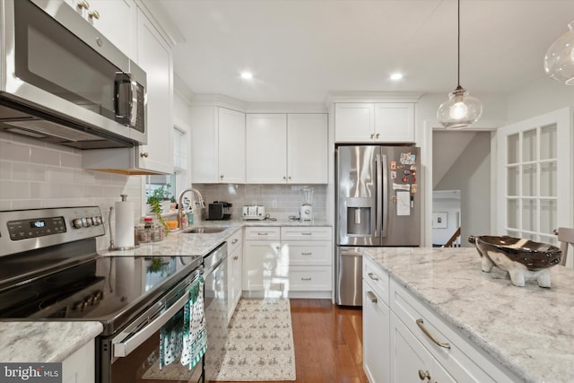 kitchen featuring dark wood-style flooring, a sink, stainless steel appliances, white cabinetry, and tasteful backsplash