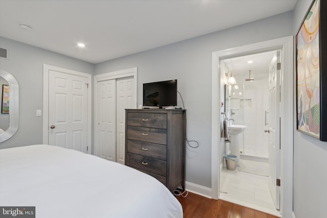 bedroom featuring visible vents, baseboards, ensuite bath, dark wood-style flooring, and a closet