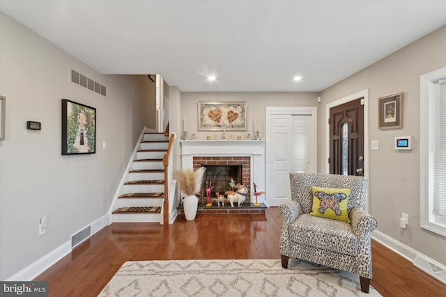 sitting room with visible vents, stairs, baseboards, and wood finished floors