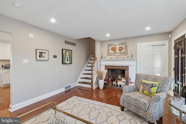 living area featuring visible vents, baseboards, wood finished floors, and stairway