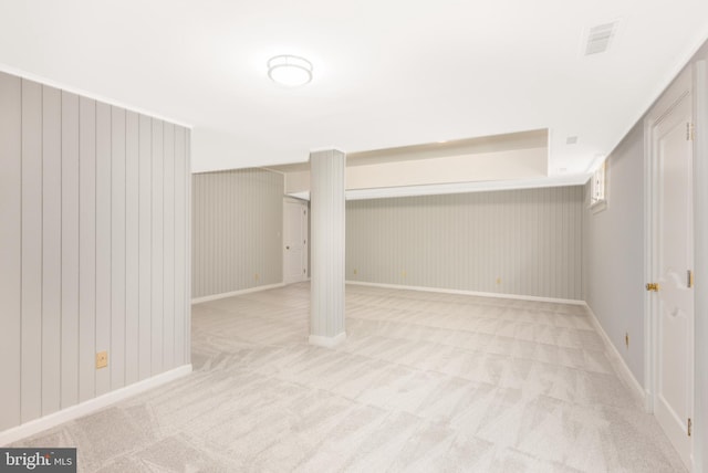 finished below grade area featuring light colored carpet, baseboards, and visible vents