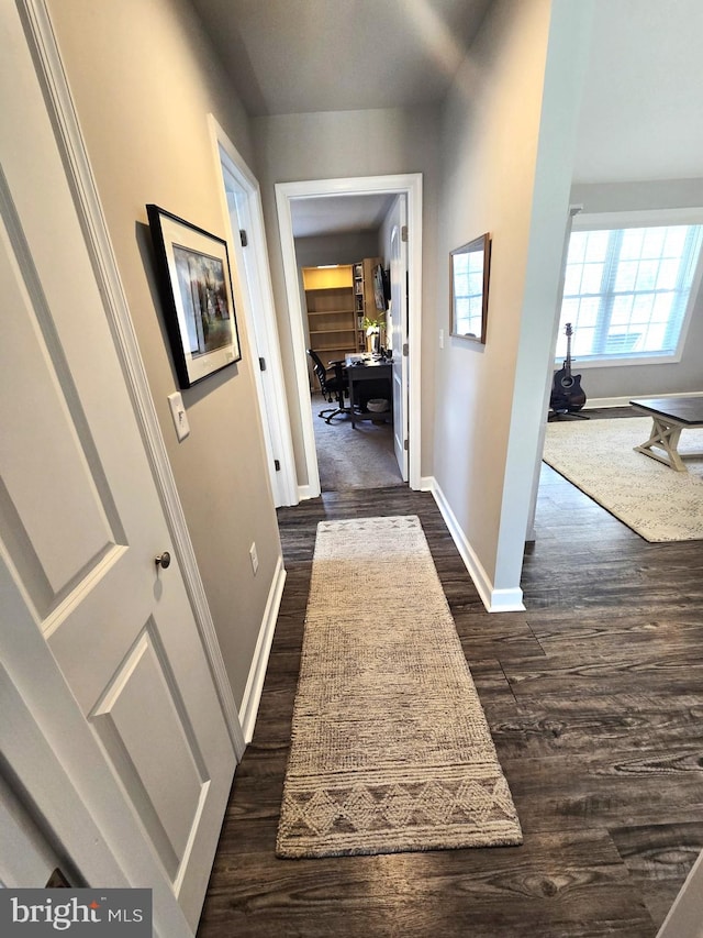 hallway featuring dark wood-style floors and baseboards