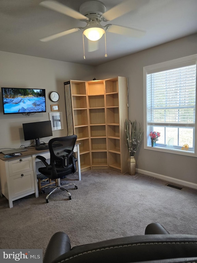 home office featuring dark colored carpet, visible vents, baseboards, and a ceiling fan