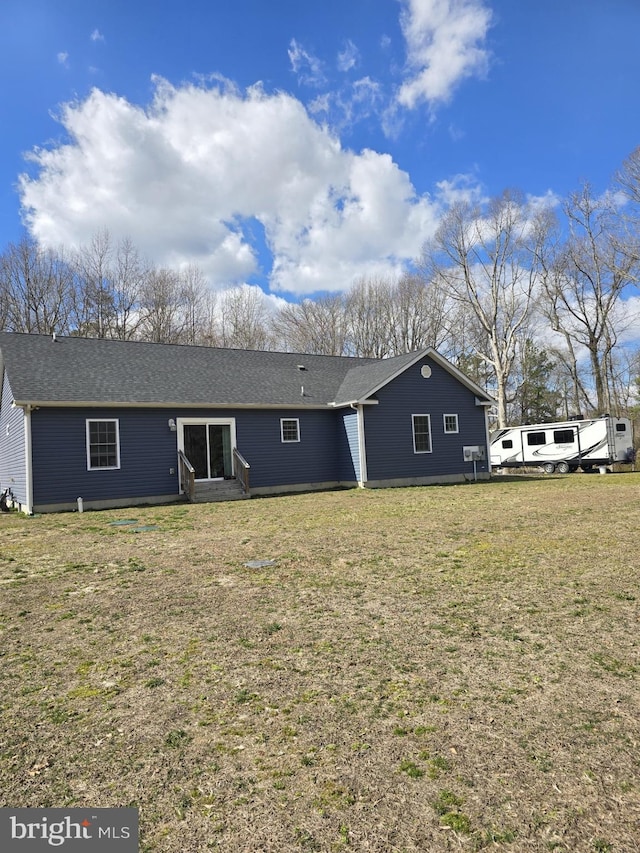 back of property with a yard and roof with shingles