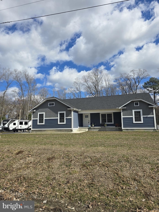 view of front of property with board and batten siding, a front lawn, and a shingled roof