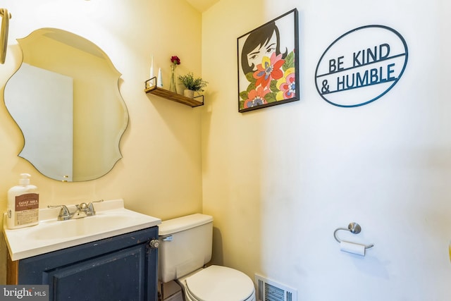 half bathroom with vanity, toilet, and visible vents