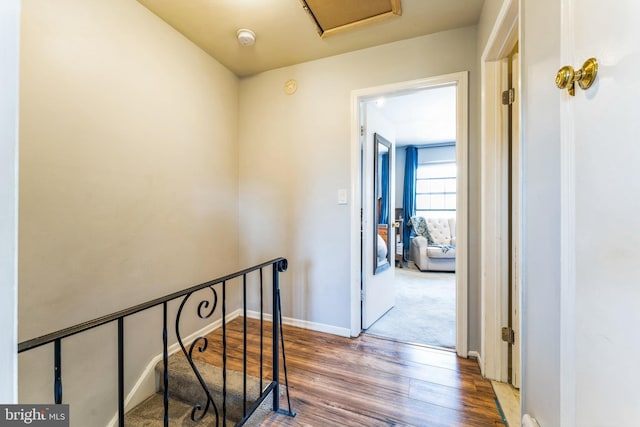 hallway with baseboards, an upstairs landing, and wood finished floors