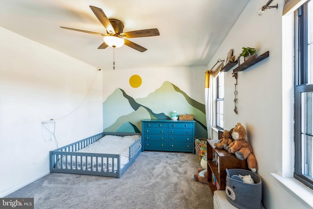 bedroom featuring carpet flooring, ceiling fan, and a nursery area