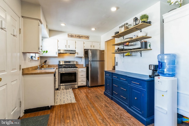 kitchen with under cabinet range hood, appliances with stainless steel finishes, white cabinets, blue cabinets, and open shelves