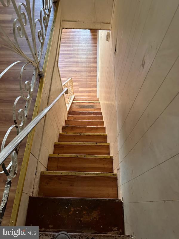 stairway featuring wooden walls