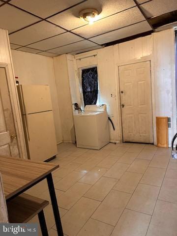 interior space featuring wooden walls, washer / clothes dryer, a paneled ceiling, and freestanding refrigerator