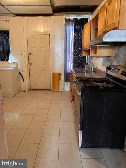 kitchen with under cabinet range hood, washer / dryer, light tile patterned flooring, electric range, and a sink